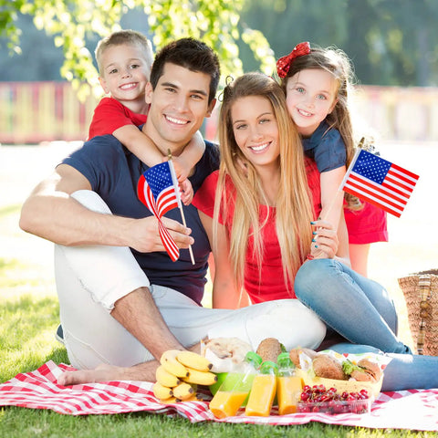 Family holding 40 Pack Small American Flags On Sticks 4 By 6 Inch Mini Flags for 4th of July, picnic setting, kid-safe wooden sticks