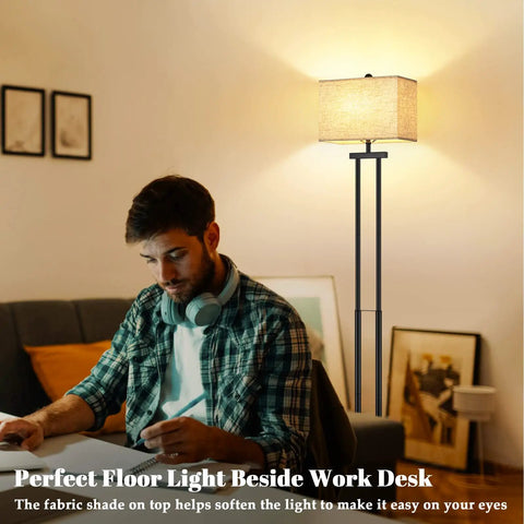 Modern Black Floor Lamp With Dual Poles And Fabric Shade Tall Reading Lamp With Foot Switch For Living Room Bedroom Office And Nursery Contemporary Farmhouse Style next to a man working at a desk.