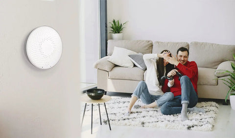 Couple in living room with Smart Radon Detector With Humidity And Temperature Sensor for home safety on wall