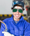 Built Different Welding Safety Goggles With Top Shelf Impact Resistance And Dust Splash Proof Black Gray Lenses For Heavy Duty Shop Work And Everyday Welder Gear worn by smiling worker in blue jacket.