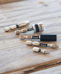 Assorted metal drill driver bits on a wooden surface, including a Beefy Impact Driver Socket Adapter Quarter Inch Square Drive Two Inch Length With Rock Solid Retention Ball For No Slip Socket Install Calibrated Heat Treated Durability For High Torque Jobs Essential Tool Accessory.