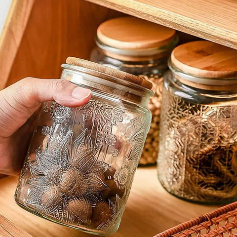 Hand holding Vintage Glass Jar With Lid 23.7oz Airtight Food Storage embossed with sunflowers, perfect for pantry decor.