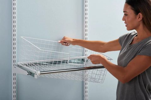 Woman installing a white Sliding Basket For Closet Organization, White, Sturdy Pull Out Wire Drawer on wall-mounted rails