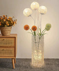 Pastoral LED Floor Lamp With Handwoven Rattan Flower Shade next to wooden dresser in cozy living room setting.