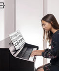 Girl at piano using 11 By 14 Inch Keyboard Practice Dry Erase Lapboard Double Sided Music Staff Whiteboard For Kids Students Musicians Portable Durable Masonite Lap Pad For Music Class Supplies, showing music notes and staff lines.