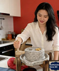 No Fuss Manual Stone Grain Mill With Hand Crank For Dry And Wet Grinding in kitchen, woman demonstrating use, natural wood base.