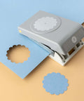 2 Inch Scallop Circle Paper Punch For Scrapbooks And Card Making, gray metal craft punch with lockable stackable design on blue paper