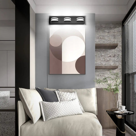 LED Modern Black Vanity Light With Acrylic Finish Over Mirror Three Light Bathroom Wall Fixture With 360 Degree Rotatable Joint And Up And Down Lighting mounted on wall above artwork in living space.