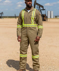 Workhorse Flame Resistant Coveralls Featuring Bold High Visibility Striping And Soft Cotton Nylon Blend For Straight Up Comfortable Daily Hazardous Environment Safety Wear worn by man outdoors.