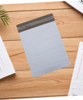 White Poly Mailer Bags 100 Pack 10x14 Inch Waterproof Self Seal Envelopes on wooden surface with calendars