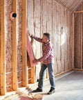 Pro Grade R13 Kraft Fiberglass Roll Insulation for 2x4 walls being installed between studs in a home under construction.
