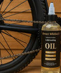 Bottle of Rugged Industrial Lubricating Oil For Tools And Machinery With Rust Prevention beside a bicycle chain