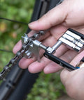 Hands using Compact Bicycle Multi Tool With CO2 Inflator And Chain Tool For Road And Mountain Bikes Torx Hex Screwdriver Set on chain