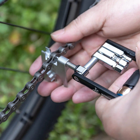 Hands using Compact Bicycle Multi Tool With CO2 Inflator And Chain Tool For Road And Mountain Bikes Torx Hex Screwdriver Set on chain