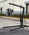 Built Like A Tank 2 Ton Folding Engine Hoist Crane with six swivel casters lifting an engine in a garage setting.