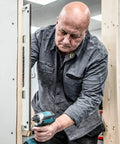 Man using No Fuss Adjustable Door Latch And Strike Plate Router Jig for precise mortise routing on a door.