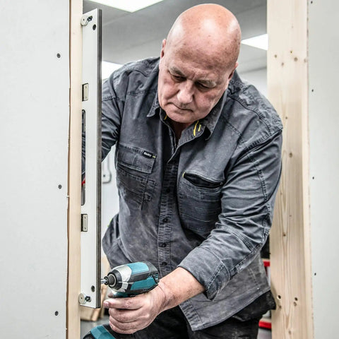 Man using No Fuss Adjustable Door Latch And Strike Plate Router Jig for precise mortise routing on a door.