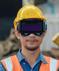 Boss Grade Auto Darkening Welding Goggles Heavy Duty Industrial Safety Glasses With Lightning Shade Switch For Grinding Soldering And Precision Steel Fabrication In Navy Blue worn by a worker with a yellow hard hat.