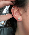 12 Pairs Hypoallergenic Pearl Stud Earrings Set For Women, Stainless Steel Posts, Multiple Sizes 5mm 6mm 8mm 10mm, Lightweight Comfort, White Composite Pearls, Everyday Go-To Jewelry. Close-up ear with 5mm and 6mm pearl studs