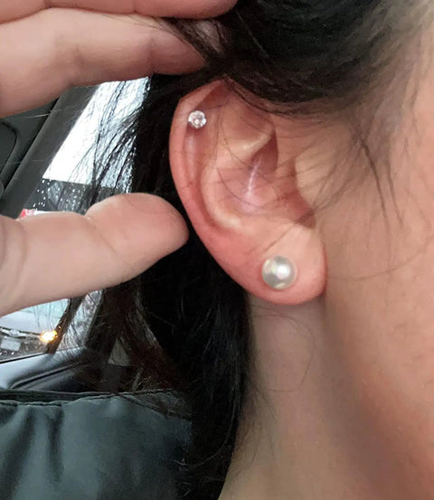 12 Pairs Hypoallergenic Pearl Stud Earrings Set For Women, Stainless Steel Posts, Multiple Sizes 5mm 6mm 8mm 10mm, Lightweight Comfort, White Composite Pearls, Everyday Go-To Jewelry. Close-up ear with 5mm and 6mm pearl studs