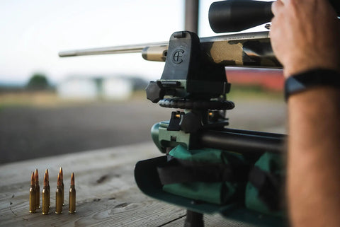 Close-up of Lead Sled DFT 2 Rifle Shooting Rest With Adjustable Ambidextrous Frame in use on a wooden table with rifle and bullets
