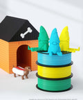 Colorful gnomes sitting on stacked blue and green filament spools with doghouse and toy dog, showcasing PLA Plus Filament's use in decoration.