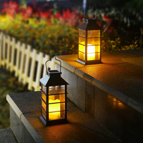 Two Pack Lit Solar Powered Outdoor Hanging Lanterns With Waterproof LED Flickering Flameless Candles on stone steps at night