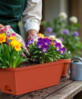Person planting flowers in a Two Pack Railing Planter Boxes With Adjustable Brackets, 16.9 Inch Window Boxes For Decks And Balconies, Red