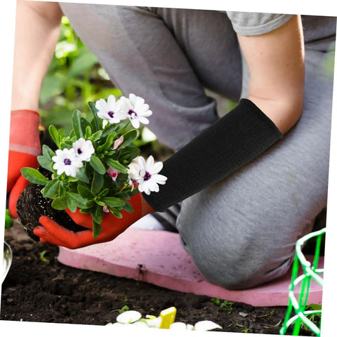 Person wearing Heavy Duty Cut Resistant Arm Sleeves Built Tough For Serious Yard And Mechanic Jobs Deliver Rock Solid Forearm Protection That Truly Holds Up Through Long Days In Matte Black while planting flowers.