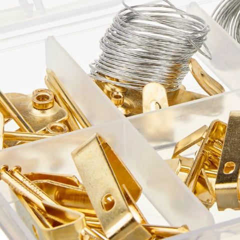 Close-up of DIY Picture Hanging Hardware Kit 220 Piece Brass Finish Set with wire, hooks, and brass hangers in a box.