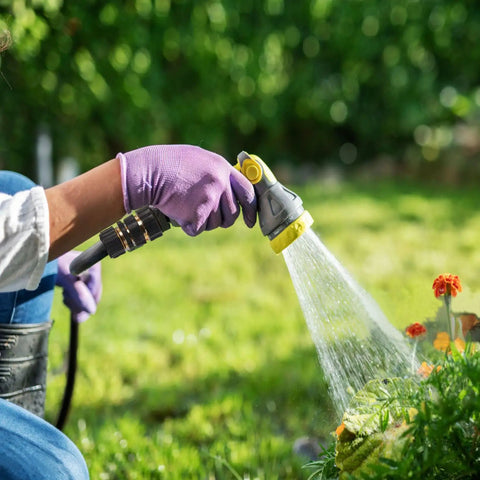 Person using a hose with premium aluminum three quarter inch garden hose quick connectors set on flowers outdoors