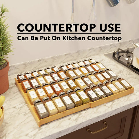 No Sweat Adjustable Bamboo Spice Drawer Organizer Expands To Fit Any Kitchen Cabinet Slot with spices on countertop.