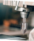 Close-up of a countersink drill bit mounted in a machine from the 5 Piece Countersink Drill Bit Set For Woodworking And Metal Fabrication With Pro Grade Precision Chamfering Tools Versatile Deburring Kit For Carpentry Projects And Metalworking Tasks.