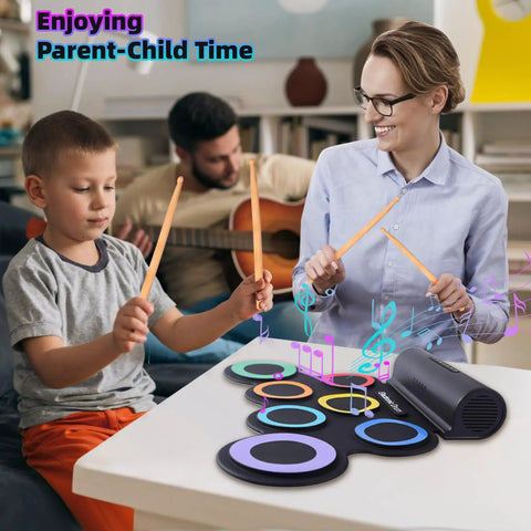 Parent and child playing Roll Up Electronic Drum Pad Kit with 7 Pads, MIDI Output, headphones, and dual speakers on a table.
