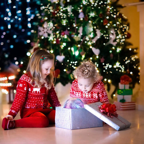 Children in holiday sweaters opening a gift box with a Galaxy Moon Lamp 4.8 Inch With Wood Stand, 16 Color Changing LED Moon Light inside.
