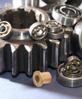 Image of Six Piece Flanged Copper Sleeve Bearings With Step Shoulder Flange And Wrapped Brass Bushings next to gears and ball bearings.