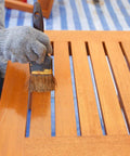 Person applying Top Shelf 100 Percent Pure Linseed Oil Wood Finish And Protective Sealer For Indoor Outdoor Furniture Plus Hardwood Surfaces Deeply Absorbs To Beat Sun And Rain Wear Keeping Grains Smooth And Radiant 32 Ounce Can on wooden slatted table.