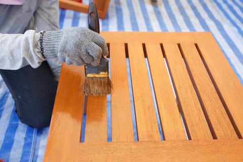 Person applying Top Shelf 100 Percent Pure Linseed Oil Wood Finish And Protective Sealer For Indoor Outdoor Furniture Plus Hardwood Surfaces Deeply Absorbs To Beat Sun And Rain Wear Keeping Grains Smooth And Radiant 32 Ounce Can on wooden slatted table.
