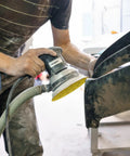 Person using random orbital sander with 135 Piece 5 Inch Sanding Discs Set Eight Hole Round Hook And Loop Gold Pro Grade Grit for auto repair.