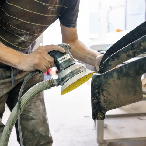 Person using random orbital sander with 135 Piece 5 Inch Sanding Discs Set Eight Hole Round Hook And Loop Gold Pro Grade Grit for auto repair.