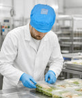Five Pack Blue Anti Static Caps Featuring Breathable Mesh Panels And Reliable Dust Blocking Defense For Cleanrooms Laboratories And Industrial Shop Grind Heavy Duty Headwear Engineered To Keep You Cool And Confident On The Daily. Worker wearing blue cap in food prep area.