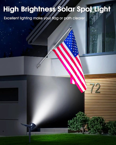 Night view of Solar Spot Lights Outdoor Waterproof IP65 Cool White 600LM illuminating a flag pole in a garden.