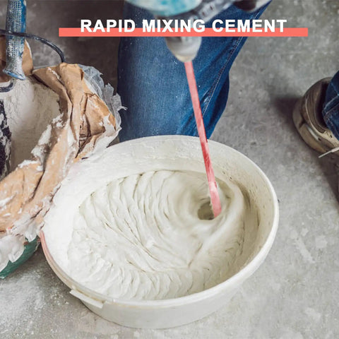 Mixing cement with a power drill in a large bucket, creating smooth paste, worker wearing jeans and sneakers visible in background.