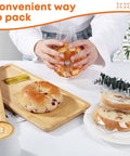 Person placing sliced bread into Clear Cellophane Treat Bags 5x7 Inches, 100 Pack With Gold 3 Inch Twist Ties For Cookies on table.