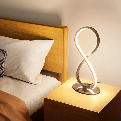 Eight Shape Spiral Led Table Lamp With Stepless Dimmable Brightness Warm White Light on a nightstand by a bed.