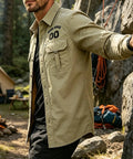 Toolbox Tested Custom Long Sleeve Work Shirt For Men Quick Dry Button Up Mechanic Uniform Personalized Utility Top Heavy Duty Green Wicking Fabric For The Daily Grind. Model outdoors by fire wearing khaki shirt.