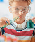Child wearing 12 Pack Safety Glasses Over Eyeglasses With Anti Fog And Scratch Resistant ANSI Z87 Protective Eyewear for experiments.