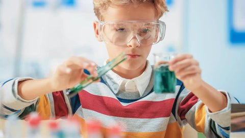 Child wearing 12 Pack Safety Glasses Over Eyeglasses With Anti Fog And Scratch Resistant ANSI Z87 Protective Eyewear for experiments.