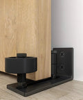 Heavy Duty Sliding Barn Door Guide With Carpet Safe Floor Track Keeps Doors Dead Center And Delivers Smooth As Butter Performance Across Any Room Zero Hassle Install And No Sweat Adjustment close-up of black steel bracket and wheel supporting wood door