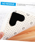 4 Pack Heart Shape Non Slip Rug Pads For Hardwood Floors And Tiles, black pad on white dotted rug corner lifted by hand
